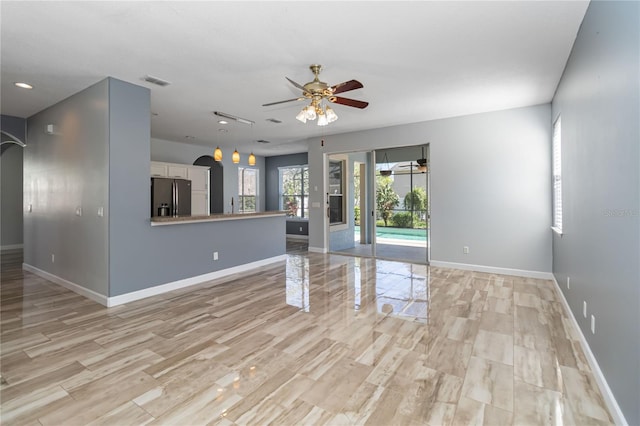 unfurnished living room with visible vents, ceiling fan, light wood finished floors, and baseboards