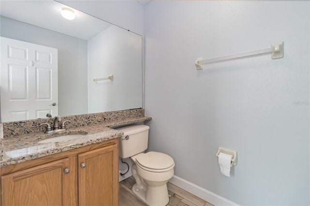 bathroom with baseboards, vanity, and toilet