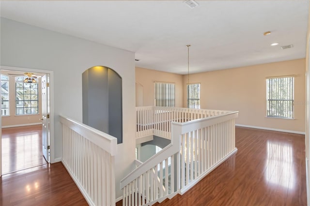 hallway featuring wood finished floors, an upstairs landing, and a healthy amount of sunlight