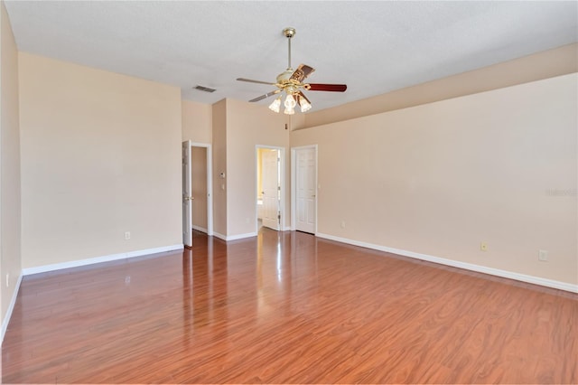 spare room featuring visible vents, ceiling fan, a textured ceiling, wood finished floors, and baseboards