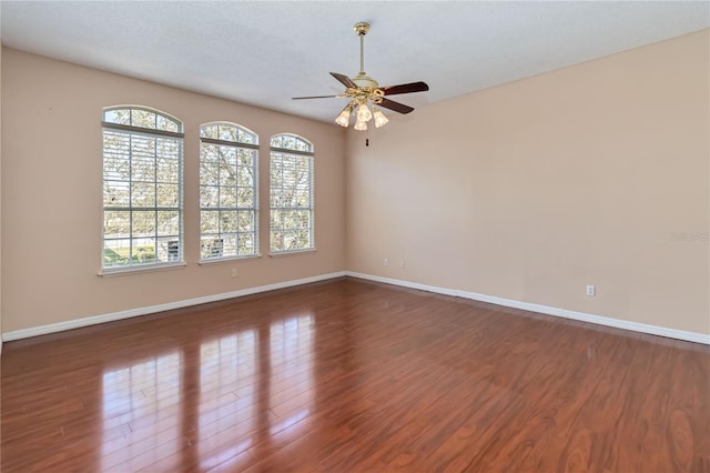 spare room with ceiling fan, a textured ceiling, wood finished floors, and baseboards