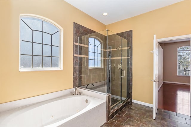 bathroom with baseboards, a shower stall, and a whirlpool tub