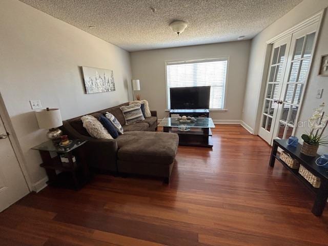 living area with french doors, a textured ceiling, baseboards, and wood finished floors