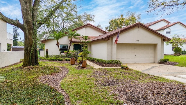 mediterranean / spanish home featuring a garage, driveway, a tiled roof, fence, and stucco siding