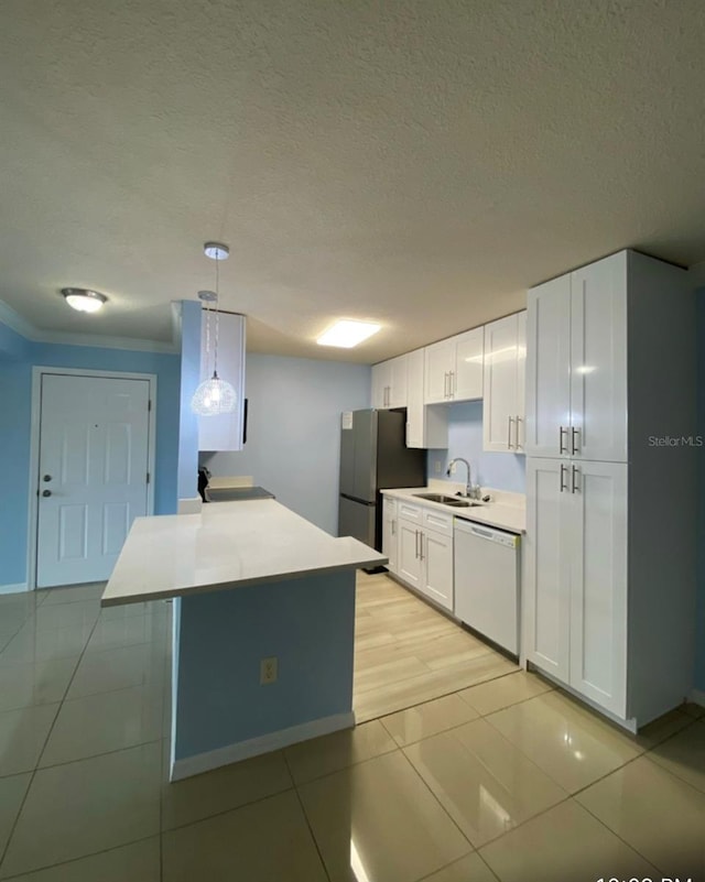 kitchen featuring white cabinets, freestanding refrigerator, white dishwasher, light countertops, and a sink