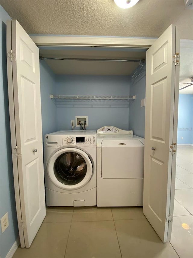 washroom featuring laundry area, light tile patterned flooring, washer and clothes dryer, and a textured ceiling