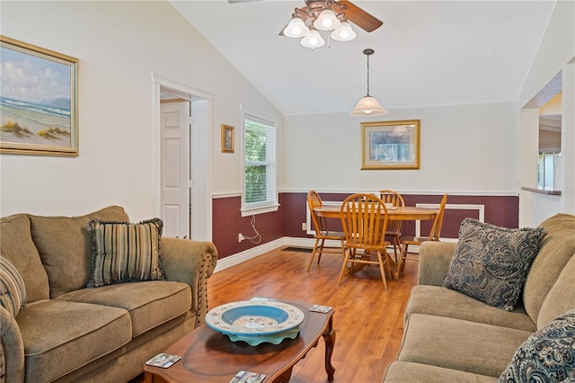 living area featuring baseboards, a ceiling fan, vaulted ceiling, and wood finished floors