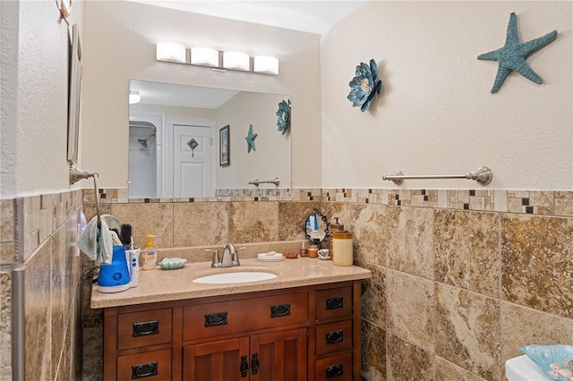 bathroom featuring a wainscoted wall, vanity, and tile walls