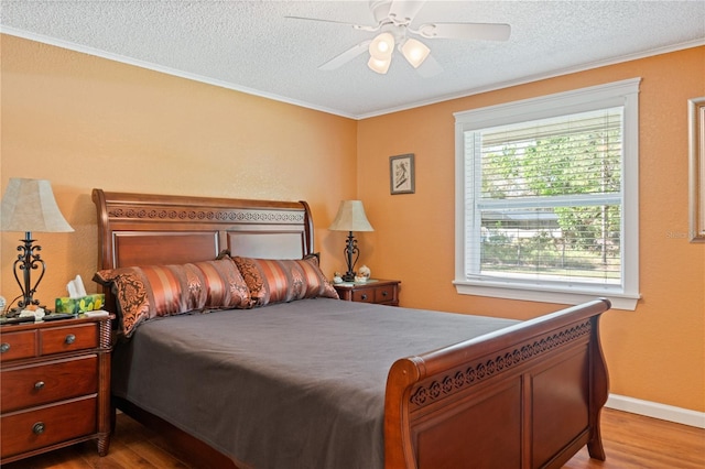 bedroom featuring a textured ceiling, wood finished floors, a ceiling fan, and crown molding