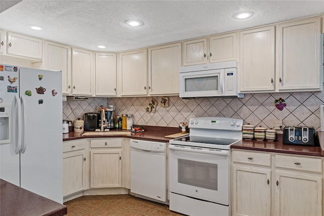 kitchen featuring tasteful backsplash, dark countertops, white appliances, and light tile patterned floors