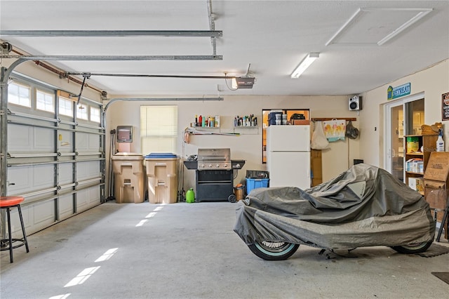 garage featuring a garage door opener and freestanding refrigerator