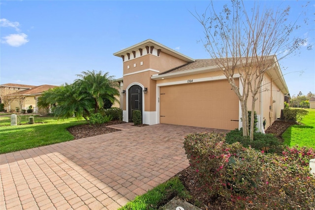 view of front of house with a garage, decorative driveway, a front lawn, and stucco siding