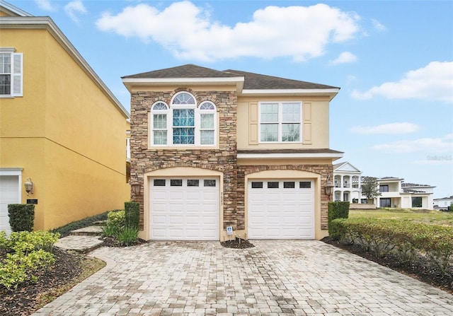 exterior space featuring a garage, decorative driveway, and stone siding