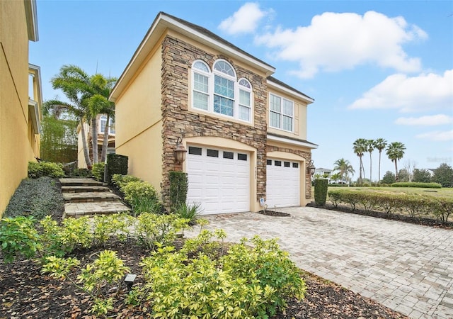 view of property exterior with stone siding, decorative driveway, an attached garage, and stucco siding