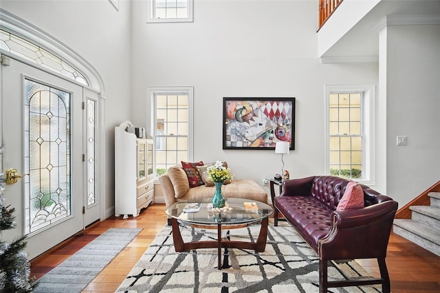 interior space with light wood-type flooring, stairs, a wealth of natural light, and a towering ceiling