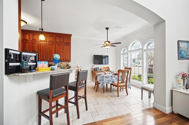 kitchen with tasteful backsplash, a breakfast bar area, ornamental molding, a peninsula, and pendant lighting