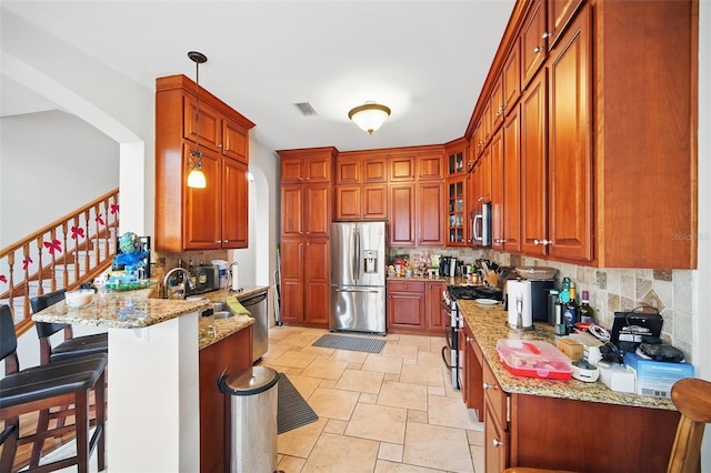 kitchen with appliances with stainless steel finishes, decorative light fixtures, glass insert cabinets, and light stone countertops