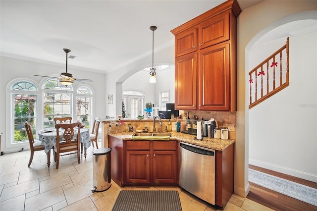 kitchen with decorative light fixtures, stainless steel dishwasher, a sink, light stone countertops, and a peninsula