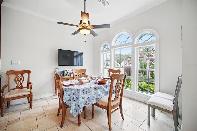 dining space with a ceiling fan, baseboards, visible vents, and crown molding