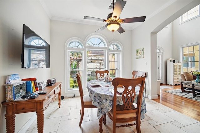 dining room featuring a ceiling fan, crown molding, light wood finished floors, and baseboards