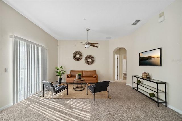 living area featuring baseboards, visible vents, arched walkways, ceiling fan, and carpet flooring