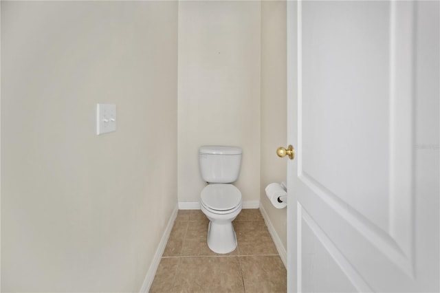 bathroom with toilet, baseboards, and tile patterned floors