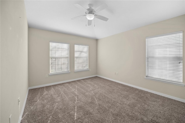 empty room featuring lofted ceiling, carpet floors, a ceiling fan, and baseboards