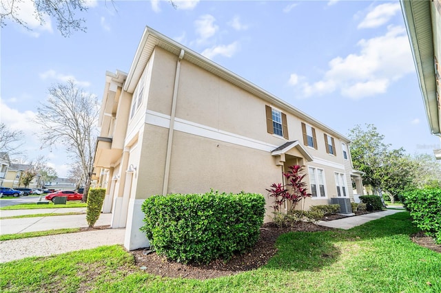 view of home's exterior featuring central air condition unit, a lawn, and stucco siding