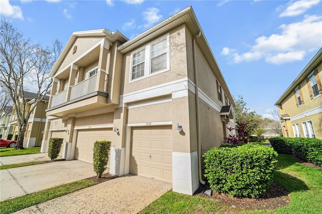 view of front of home with driveway, an attached garage, a balcony, and stucco siding