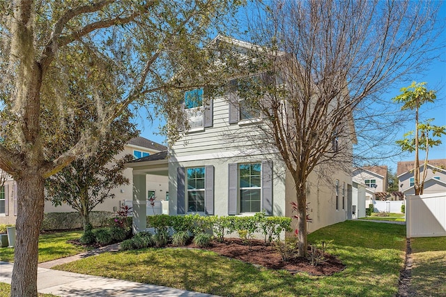 view of front of house with a front yard, fence, and stucco siding