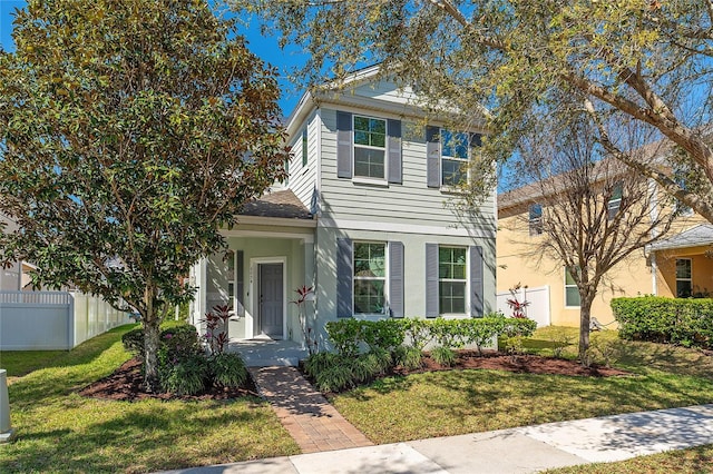 traditional home featuring fence and a front lawn