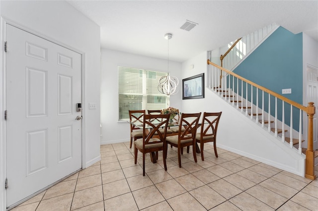 dining room with a notable chandelier, visible vents, light tile patterned flooring, baseboards, and stairs