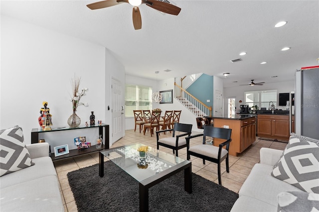 living area featuring recessed lighting, light tile patterned floors, visible vents, and stairs