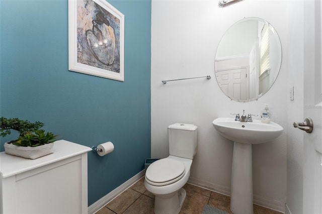 bathroom with a sink, tile patterned flooring, toilet, and baseboards