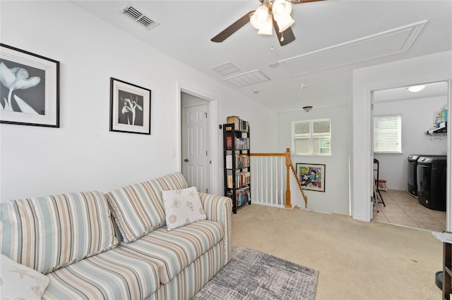 living area with light carpet, attic access, visible vents, and washing machine and clothes dryer