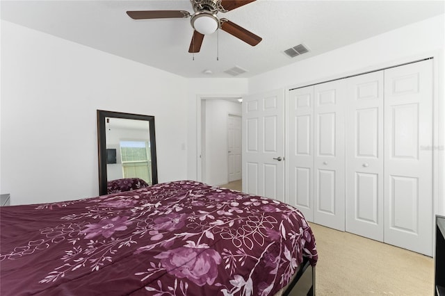 carpeted bedroom with ceiling fan, a closet, and visible vents