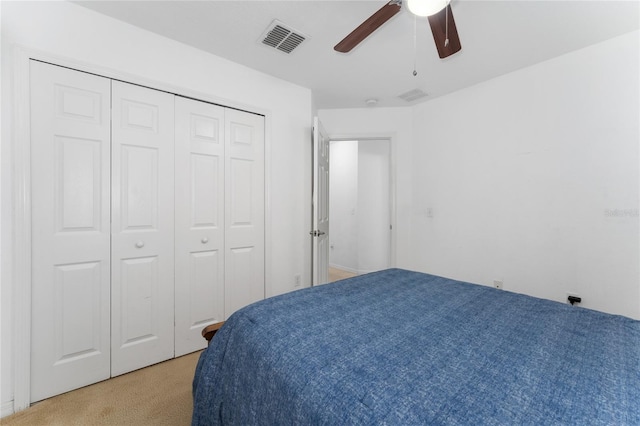 bedroom featuring ceiling fan, a closet, visible vents, and light colored carpet