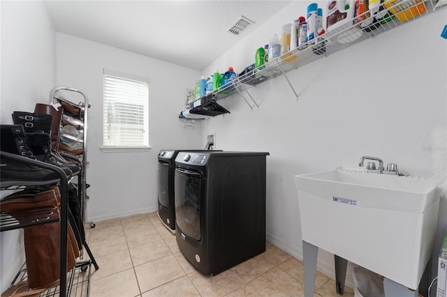 washroom with laundry area, light tile patterned floors, visible vents, independent washer and dryer, and a sink