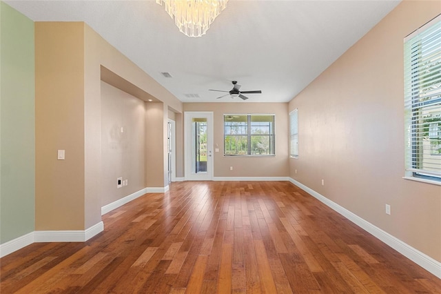 unfurnished room with visible vents, ceiling fan with notable chandelier, light wood-type flooring, and baseboards