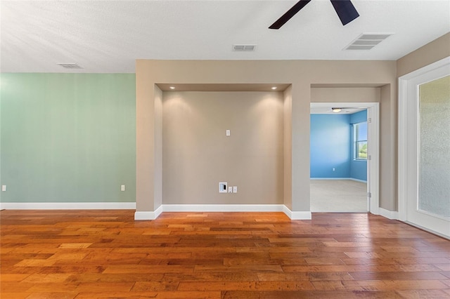 unfurnished room with hardwood / wood-style floors, baseboards, and visible vents