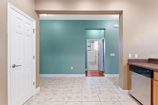 kitchen with dishwasher, dark countertops, light tile patterned floors, and baseboards