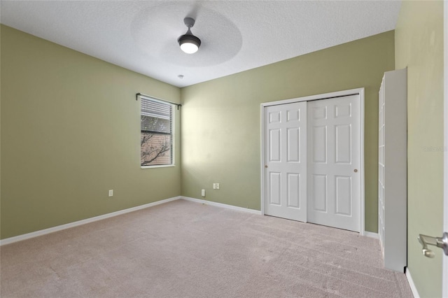 unfurnished bedroom with a ceiling fan, a textured ceiling, a closet, carpet floors, and baseboards