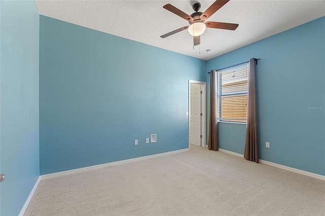 carpeted spare room with ceiling fan, a textured ceiling, and baseboards