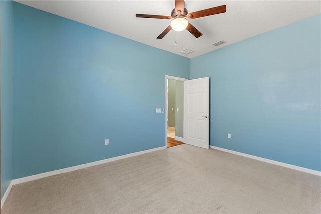 spare room with visible vents, carpet, baseboards, a textured ceiling, and a ceiling fan