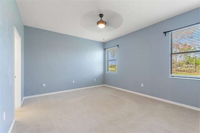 carpeted empty room with a ceiling fan and baseboards