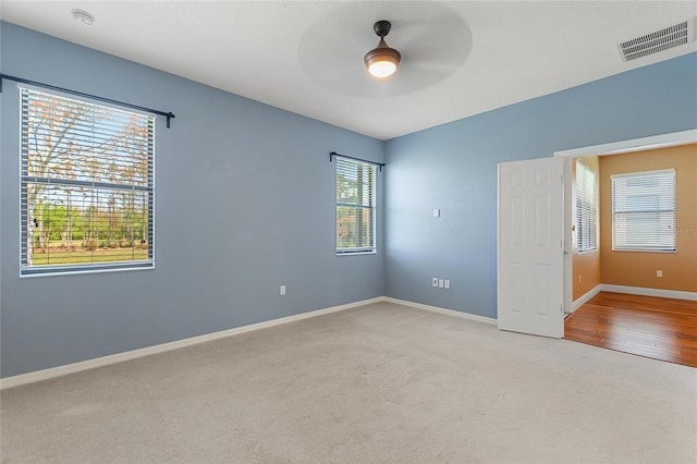 carpeted spare room with baseboards, visible vents, and ceiling fan