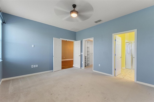 unfurnished bedroom featuring baseboards, visible vents, carpet floors, a closet, and a walk in closet