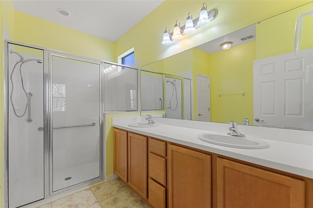 bathroom with a sink, double vanity, a shower stall, and tile patterned floors