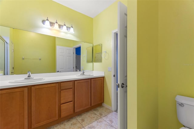 full bath featuring a sink, toilet, double vanity, and tile patterned flooring