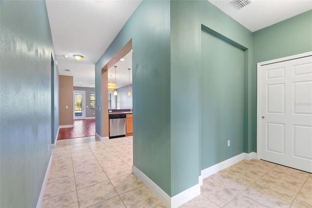 hallway with light tile patterned flooring, baseboards, and visible vents